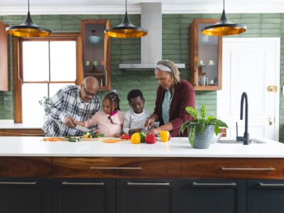 Happy african american grandparents and grandchildren chopping vegetables in kitchen, slow motion