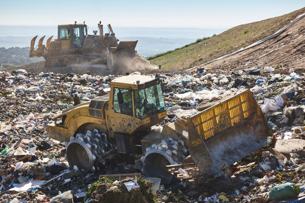 Heavy machinery shredding garbage in an open air landfill. Pollution